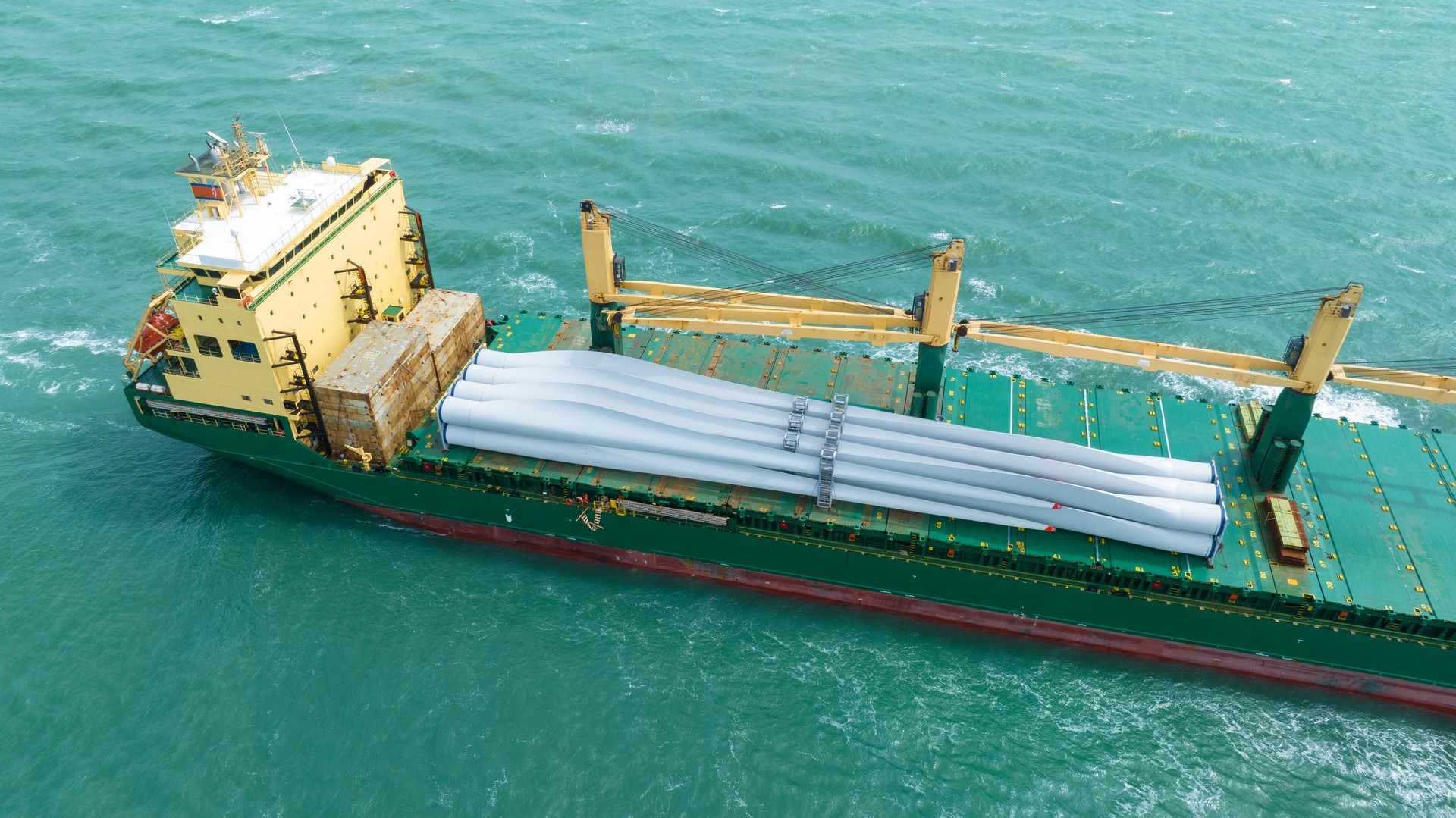 Wind Turbine on Ship, Transportation of blades for wind turbines on a cargo ship. Heavy load carrier on cargo ship loaded with Electric Wind Turbine Blades.